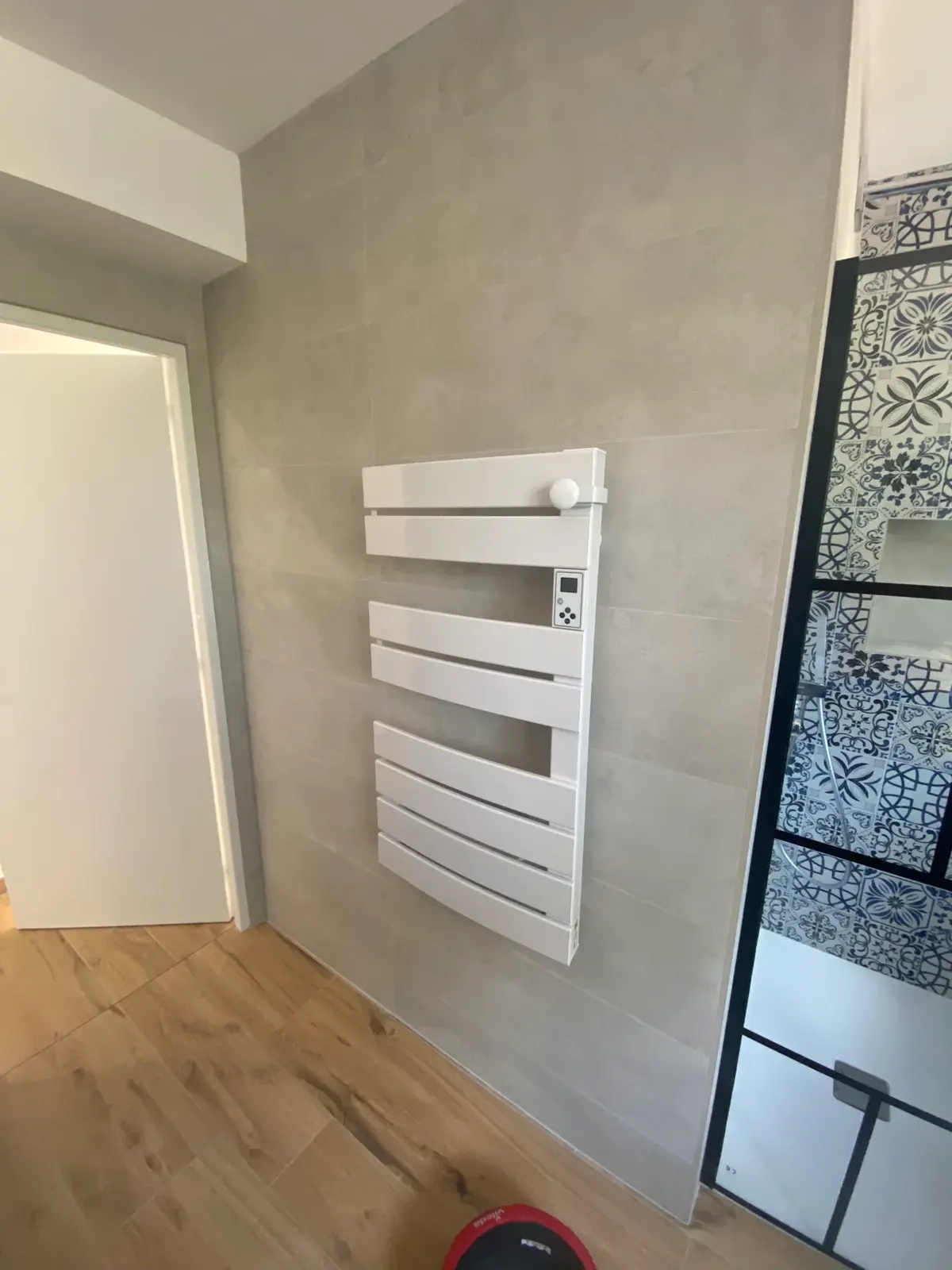 Sèche-serviettes et douche verrière dans une salle de bain rénovée